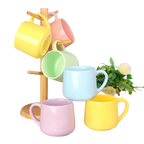 Six colorful ceramic mugs displayed beside a wooden mug stand