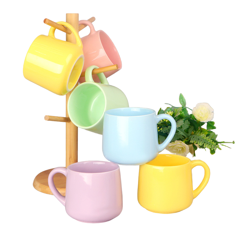 Six colorful ceramic mugs displayed beside a wooden mug stand