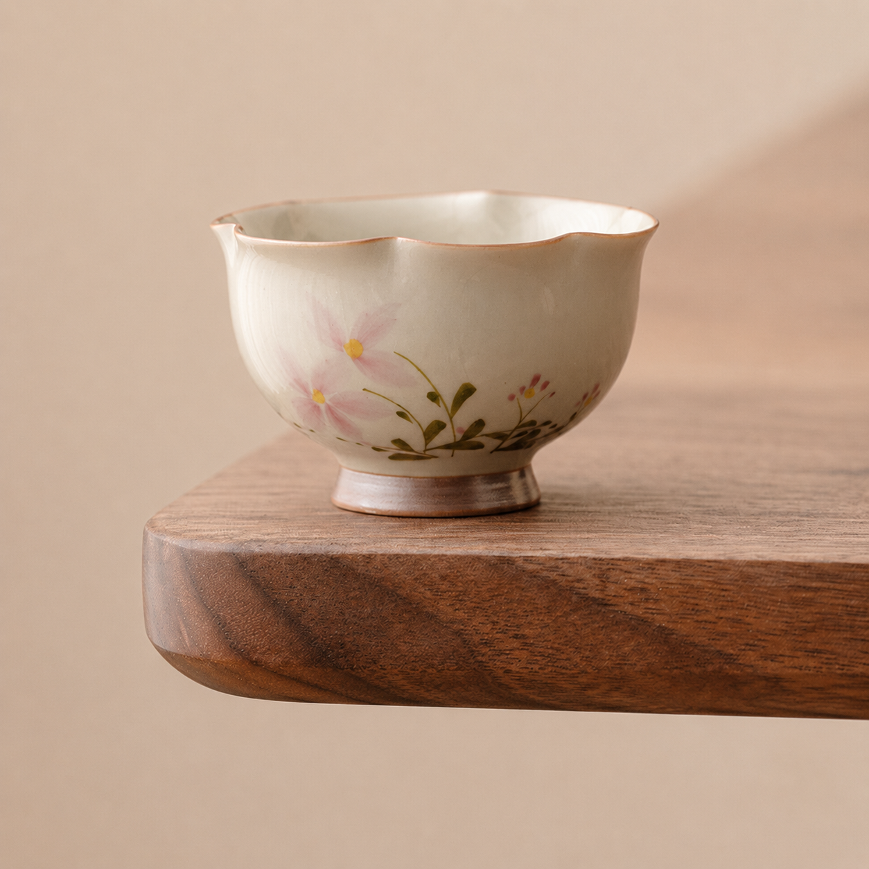 Matching ivory ceramic tea cup with pink flowers, footed base and shaped rim
