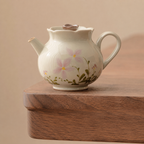 Ivory ceramic teapot with pink floral pattern, lid, handle and pouring spout