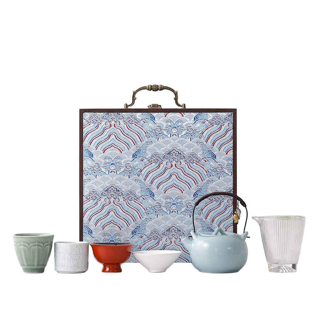 Portable ceramic tea set with four assorted cups, glass pitcher, pale blue teapot and blue wave-pattern hard case