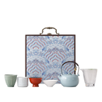 Portable ceramic tea set with four assorted cups, glass pitcher, pale blue teapot and blue wave-pattern hard case