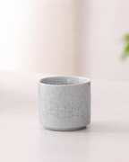 Pale cylindrical ceramic tea cup with decorative crackle-pattern glaze