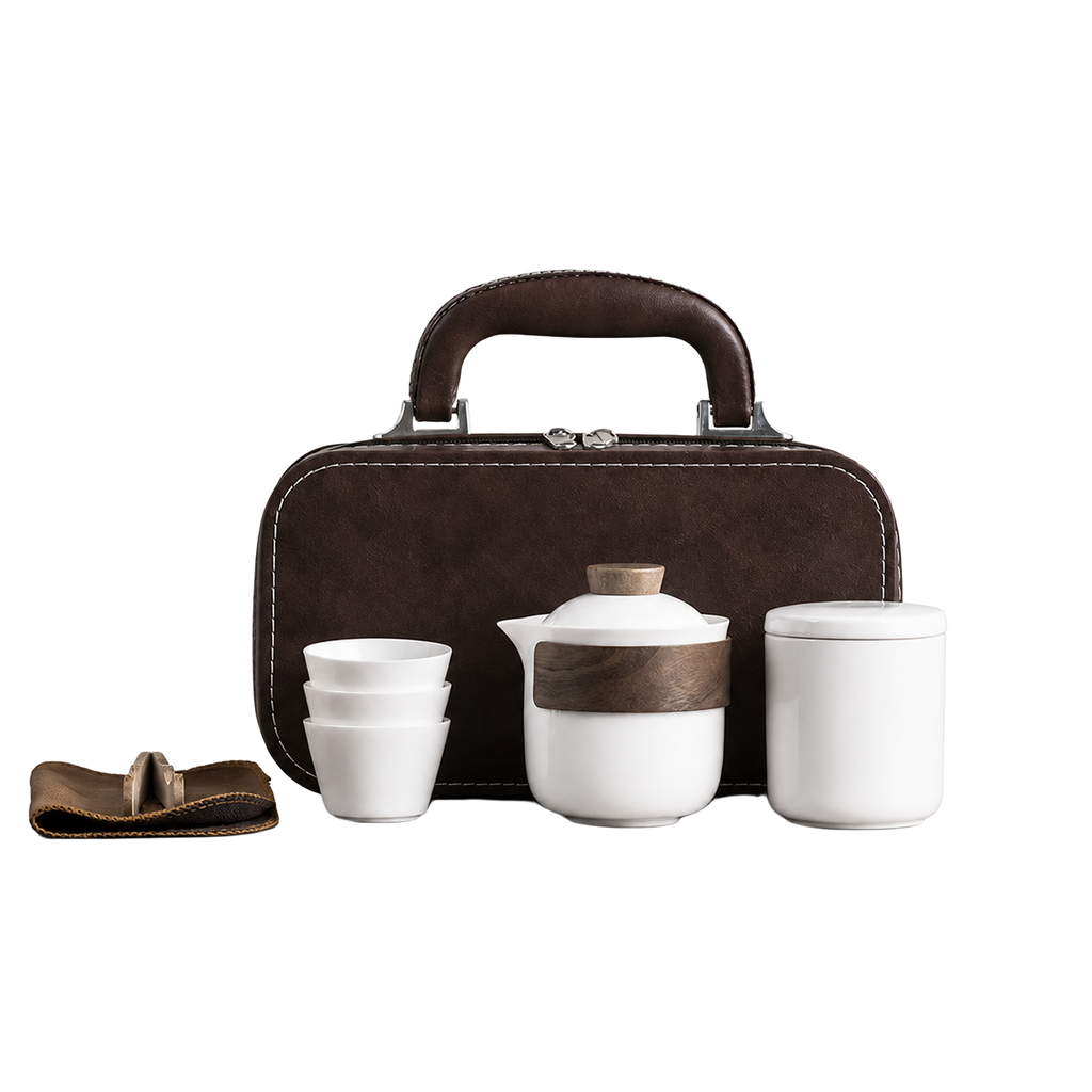 White ceramic travel tea set with teapot, three cups, lidded container, accessory wrap and brown carry case