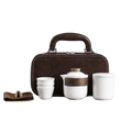 White ceramic travel tea set with teapot, three cups, lidded container, accessory wrap and brown carry case