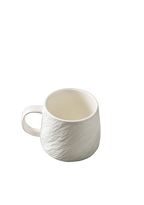 White ceramic mug with tactile stone-inspired texture, smooth rim and loop handle